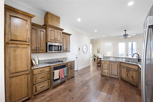 kitchen with light stone countertops, appliances with stainless steel finishes, sink, dark wood-type flooring, and ornamental molding