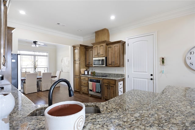 kitchen featuring appliances with stainless steel finishes, light stone countertops, ceiling fan, dark wood-type flooring, and crown molding