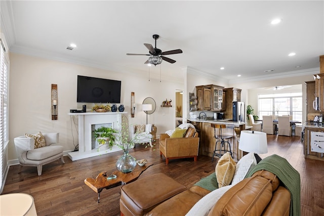 living room with crown molding, dark hardwood / wood-style flooring, and ceiling fan