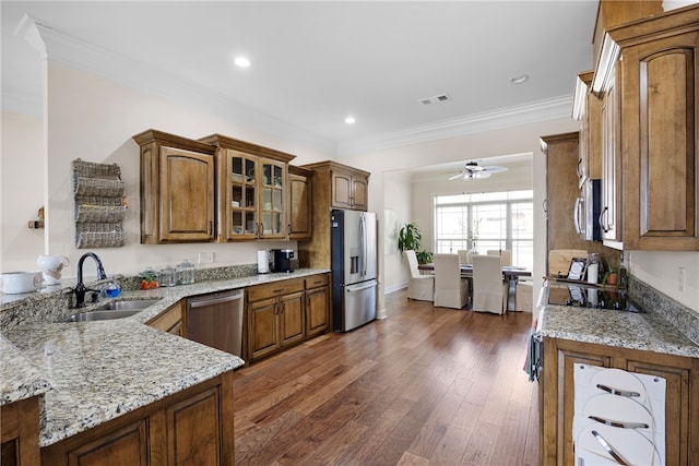 kitchen featuring sink, crown molding, appliances with stainless steel finishes, light stone counters, and dark hardwood / wood-style flooring