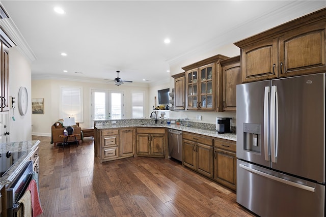 kitchen featuring dark hardwood / wood-style flooring, appliances with stainless steel finishes, light stone countertops, crown molding, and sink