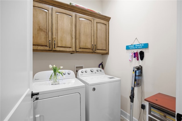 clothes washing area featuring cabinets and washer and clothes dryer