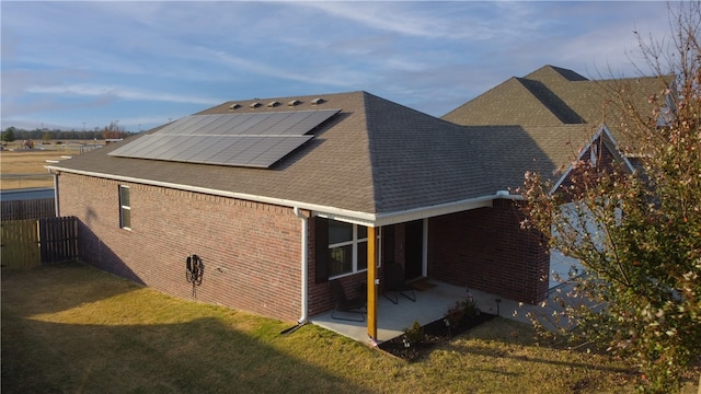 rear view of property with solar panels, a patio, and a yard