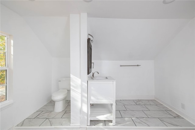 bathroom with sink, toilet, and vaulted ceiling