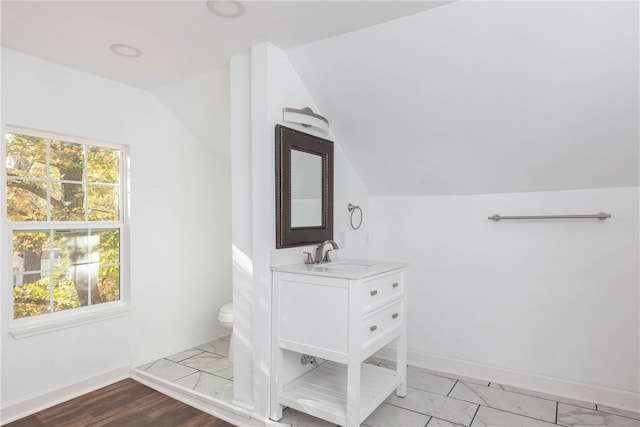 bathroom featuring vanity, toilet, lofted ceiling, and hardwood / wood-style floors