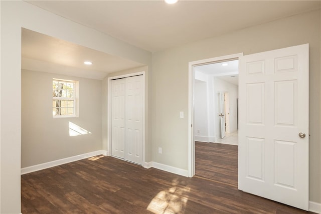 unfurnished bedroom with a closet and dark wood-type flooring