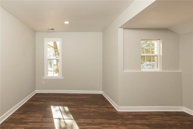 spare room with dark wood-type flooring, vaulted ceiling, and a wealth of natural light