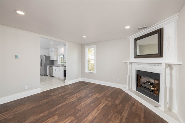 unfurnished living room featuring sink and light hardwood / wood-style floors