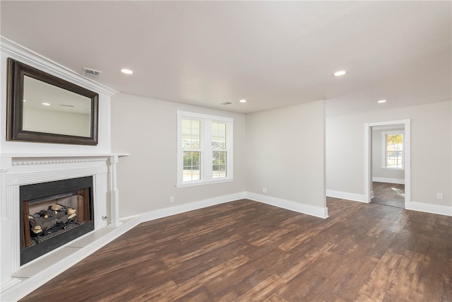 unfurnished living room with dark hardwood / wood-style flooring and a wealth of natural light