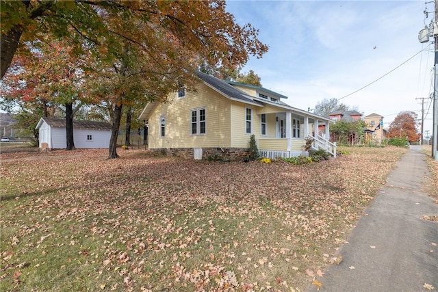 view of side of property with a garage, an outbuilding, and a porch