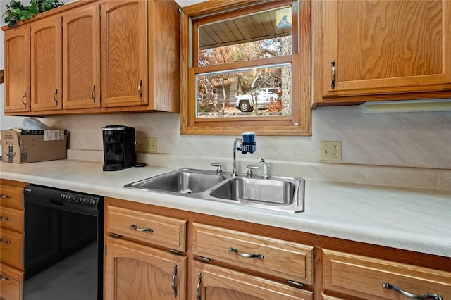 kitchen featuring black dishwasher, light countertops, brown cabinetry, and a sink