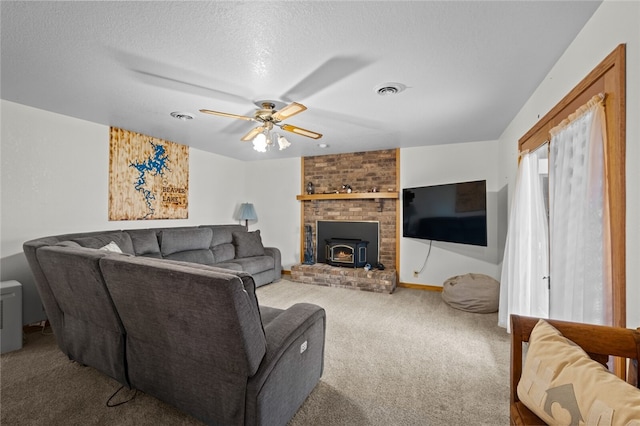 carpeted living area with a ceiling fan, a wood stove, visible vents, and a textured ceiling