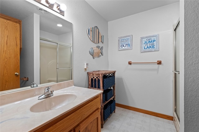 bathroom featuring a shower with shower door, vanity, baseboards, and tile patterned floors