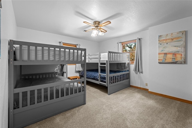 carpeted bedroom featuring ceiling fan, a textured ceiling, and baseboards