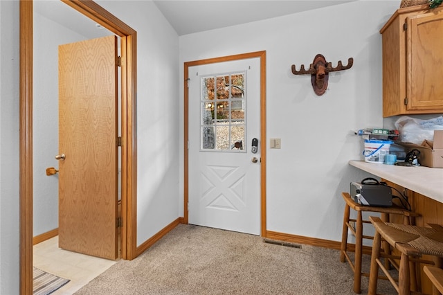 doorway to outside with visible vents, light carpet, and baseboards