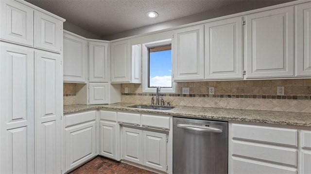 kitchen with white cabinetry, dishwasher, light stone countertops, and sink