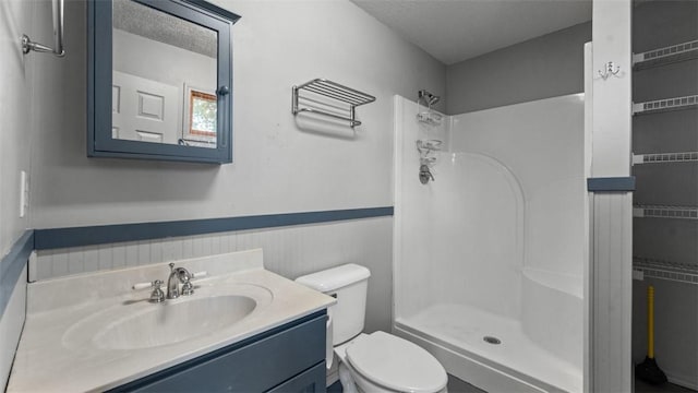 bathroom featuring walk in shower, vanity, a textured ceiling, toilet, and wood walls