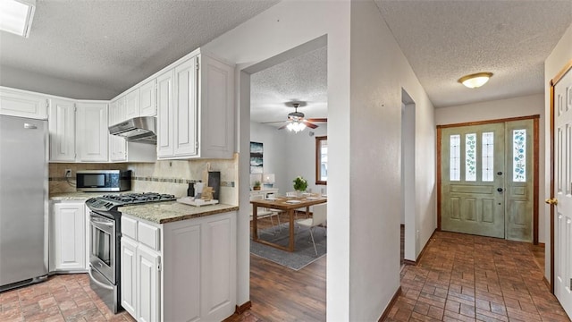 kitchen featuring decorative backsplash, light stone countertops, white cabinets, and appliances with stainless steel finishes