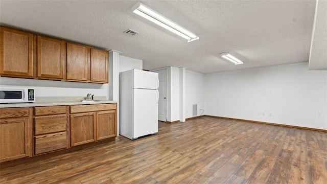 kitchen featuring dark hardwood / wood-style flooring, sink, white appliances, and a textured ceiling