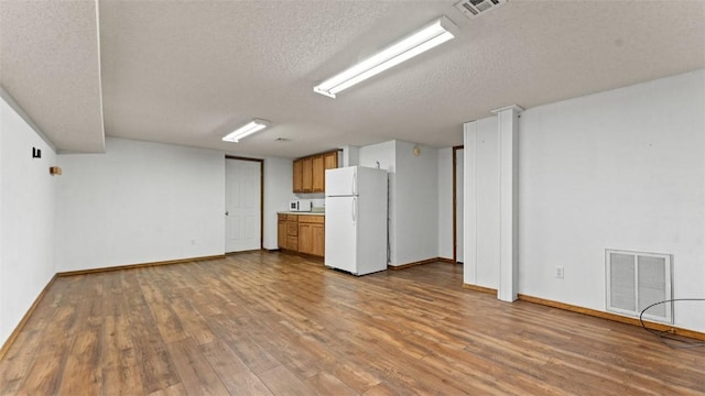 unfurnished living room featuring a textured ceiling and light hardwood / wood-style flooring