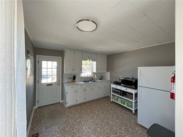 kitchen with sink, white refrigerator, and white cabinets