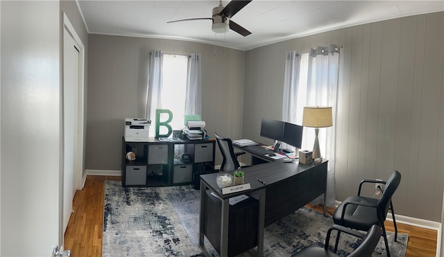 office with crown molding, hardwood / wood-style flooring, wooden walls, and ceiling fan