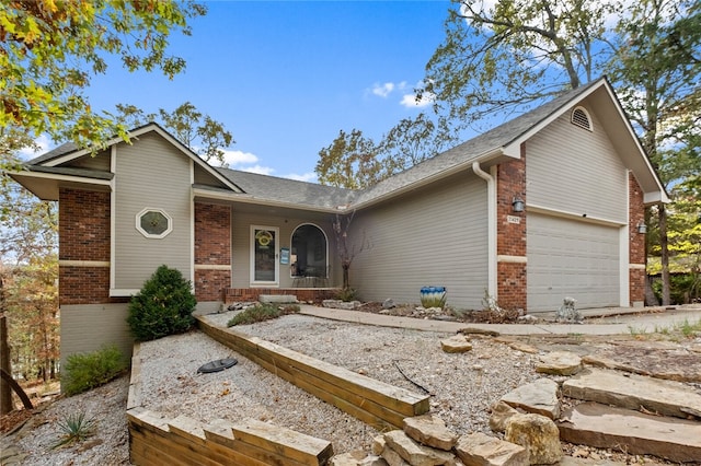 view of front of property featuring covered porch, brick siding, and an attached garage