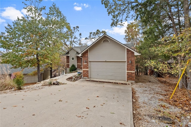 view of front of property with a garage, brick siding, driveway, and a chimney