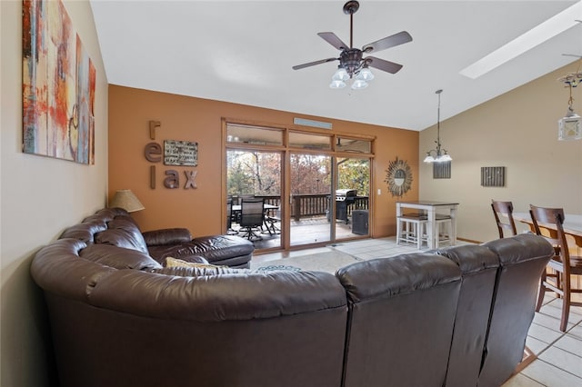 living room with vaulted ceiling with skylight, ceiling fan, and light tile patterned floors