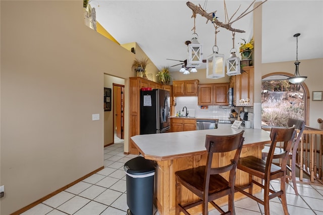 kitchen with a peninsula, vaulted ceiling, stainless steel appliances, light countertops, and a sink