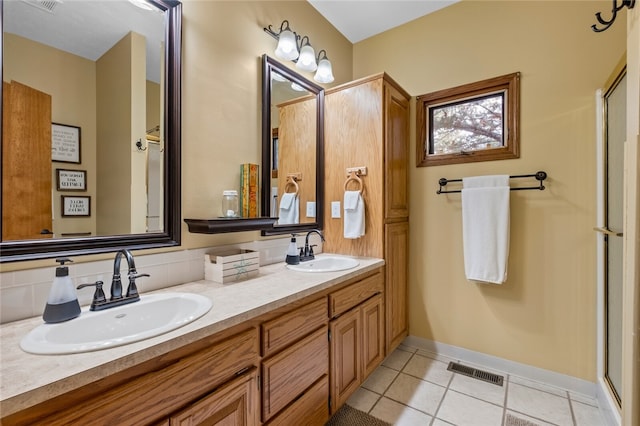 bathroom featuring a shower with door, a sink, visible vents, and tile patterned floors