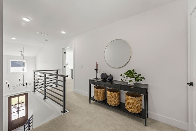 hallway with light carpet and an inviting chandelier