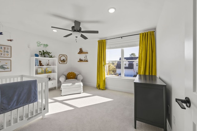 carpeted bedroom with a nursery area and ceiling fan