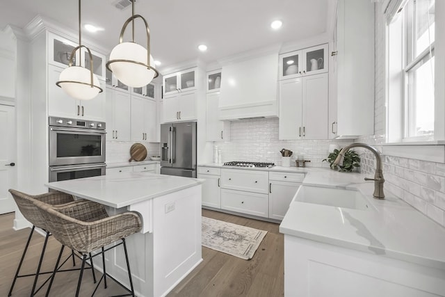 kitchen with premium range hood, sink, hanging light fixtures, a kitchen island, and stainless steel appliances