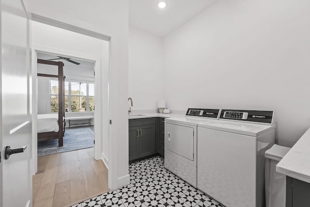 clothes washing area with sink, cabinets, washer and dryer, light wood-type flooring, and ceiling fan