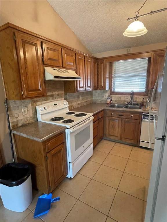 kitchen with a textured ceiling, sink, backsplash, and white appliances