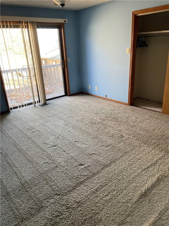 unfurnished bedroom featuring a closet, carpet, a textured ceiling, and access to exterior