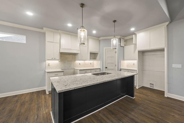 kitchen with dark wood-type flooring, white cabinetry, an island with sink, custom range hood, and light stone countertops