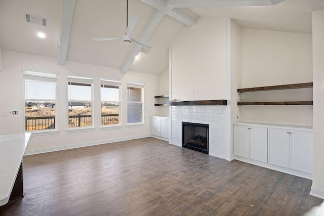 unfurnished living room with dark wood-style floors, a ceiling fan, visible vents, a fireplace, and beamed ceiling