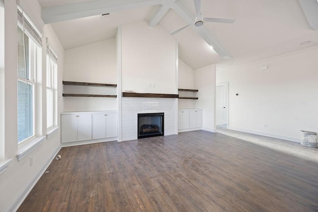 unfurnished living room with plenty of natural light, vaulted ceiling with beams, and wood finished floors