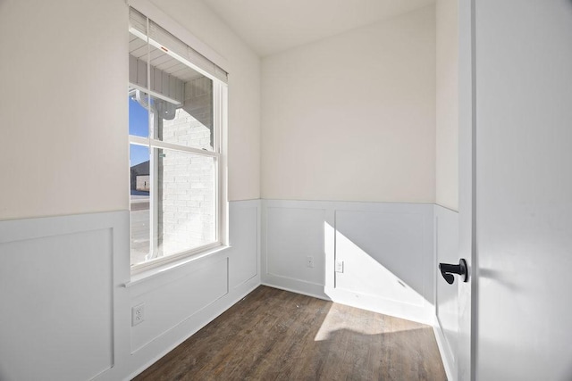 empty room featuring wood finished floors and a wainscoted wall
