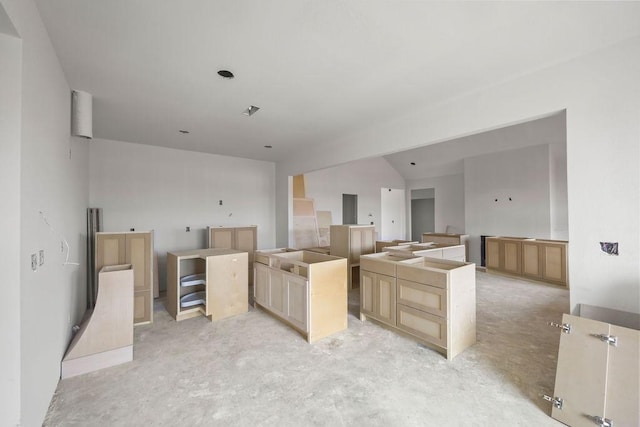 interior space featuring a center island, lofted ceiling, and light brown cabinetry