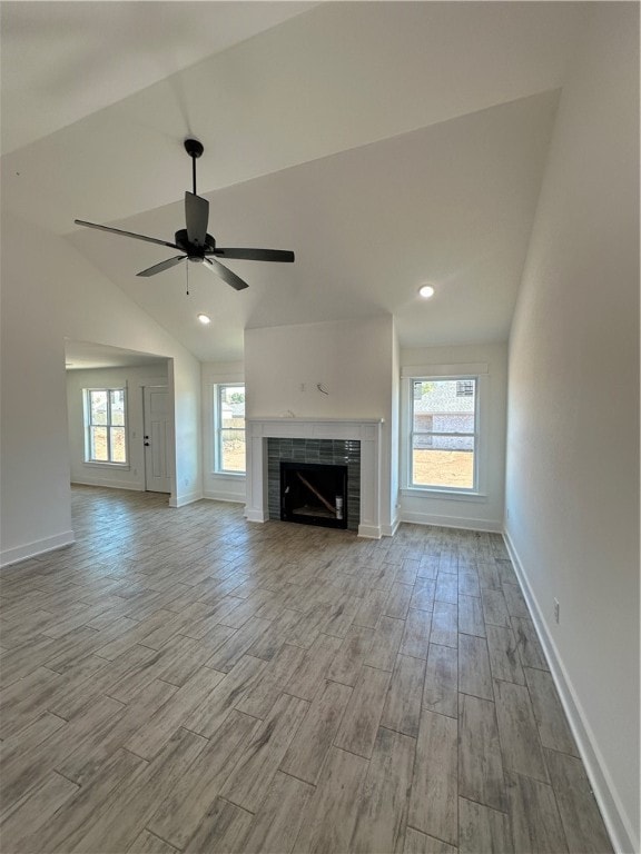 unfurnished living room featuring ceiling fan, light hardwood / wood-style floors, lofted ceiling, and a fireplace