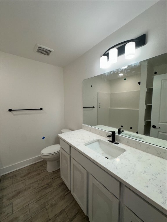 bathroom with hardwood / wood-style floors, vanity, and toilet