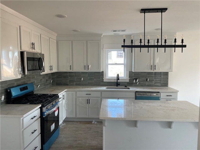 kitchen with sink, pendant lighting, a breakfast bar area, white cabinets, and appliances with stainless steel finishes