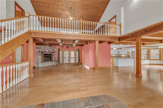 unfurnished living room with a stone fireplace, wood-type flooring, high vaulted ceiling, and wooden ceiling