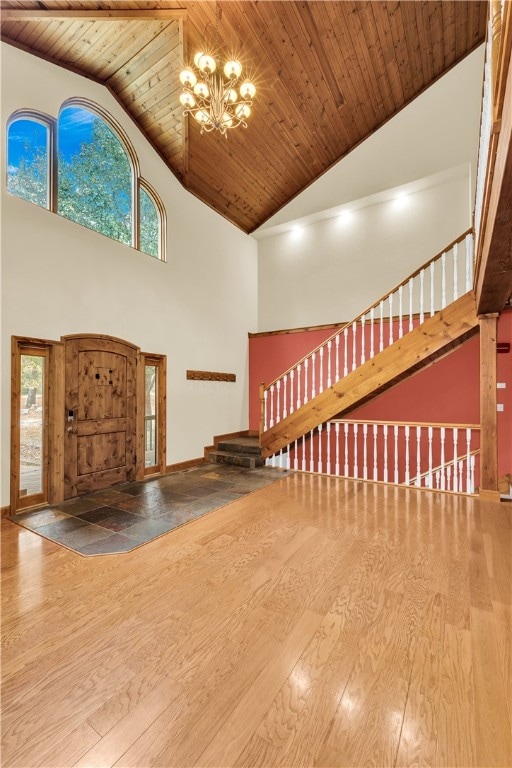 unfurnished living room with hardwood / wood-style flooring, high vaulted ceiling, wooden ceiling, and a chandelier