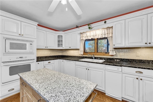 kitchen with sink, white cabinets, white appliances, and dark stone counters