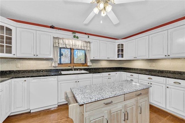 kitchen with dishwasher, dark stone countertops, sink, light wood-type flooring, and white cabinets