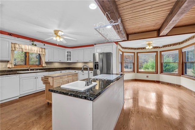 kitchen featuring stainless steel fridge with ice dispenser, an island with sink, white dishwasher, light wood-type flooring, and sink